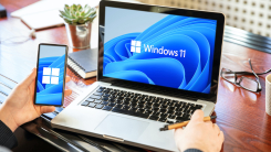 Man with a laptop and a smartphone, both runningWindows 11