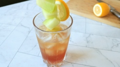 A drink with honeydew melon skewered into it.