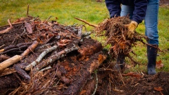 person adding biocompost to hugelkultur bed