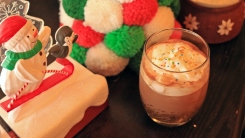 A spiked hot chocolate with whipped cream next to a snowman decoration.