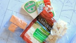 Bags, blocks, and slices of cheese in plastic freezer bags on a countertop.