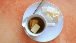 A mug of aguapanela with pieces of cheese in it.