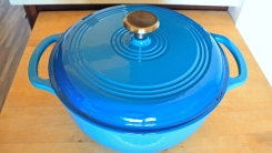 A blue dutch oven on a wooden countertop.