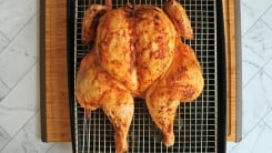 A spatchcocked roast chicken on a roasting pan