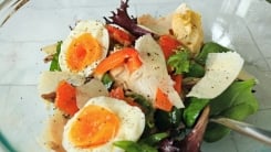 A sandwich salad with boiled eggs, shaved cheese, roasted red peppers and artichoke hearts.