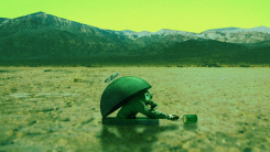 An illustration of a barren landscape. A hatch is in the muddle of the image. A person in a gas mask is emerging from in to grab a can of food lying nearby.