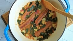 A Dutch oven pot filled with a sausage and bean stew.