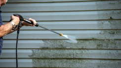 person powerwashing home exterior