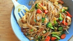 A frying pan with stir fried noodles and vegetables in it.