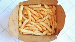 French fries packed into a brown take out box.