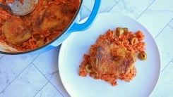 A chicken thigh on a bed of tomato rice next to a big pot of the same meal.