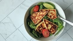 A leafy salad with griddled fried cheese on top.
