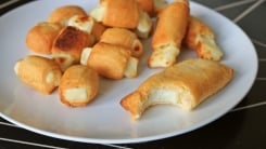 Cheese in pastry blankets on a white plate.