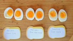 Eggs cut in half and lined up on a cutting board.