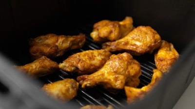 Chicken wings in an air fryer basket.