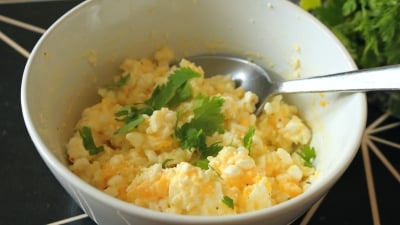 A bowl of egg salad with chopped cilantro on top. 