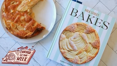A cake next to the Milk Street Bakes cookbook