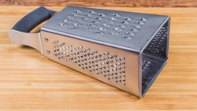 A box grater on its side on a wooden table.