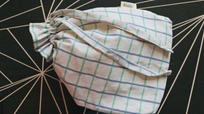 A fabric drawstring bread bag on a black table.