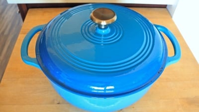 A blue dutch oven on a wooden countertop.