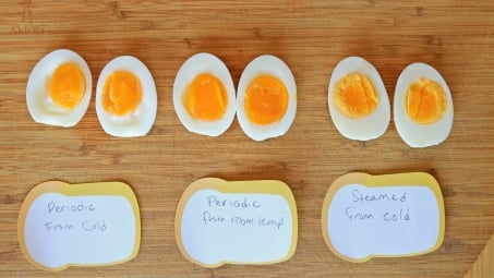 Eggs cut in half and lined up on a cutting board.
