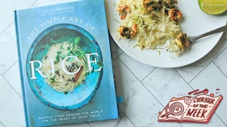 The Simple Art of Rice cookbook on a table with a plate of shrimp and rice.