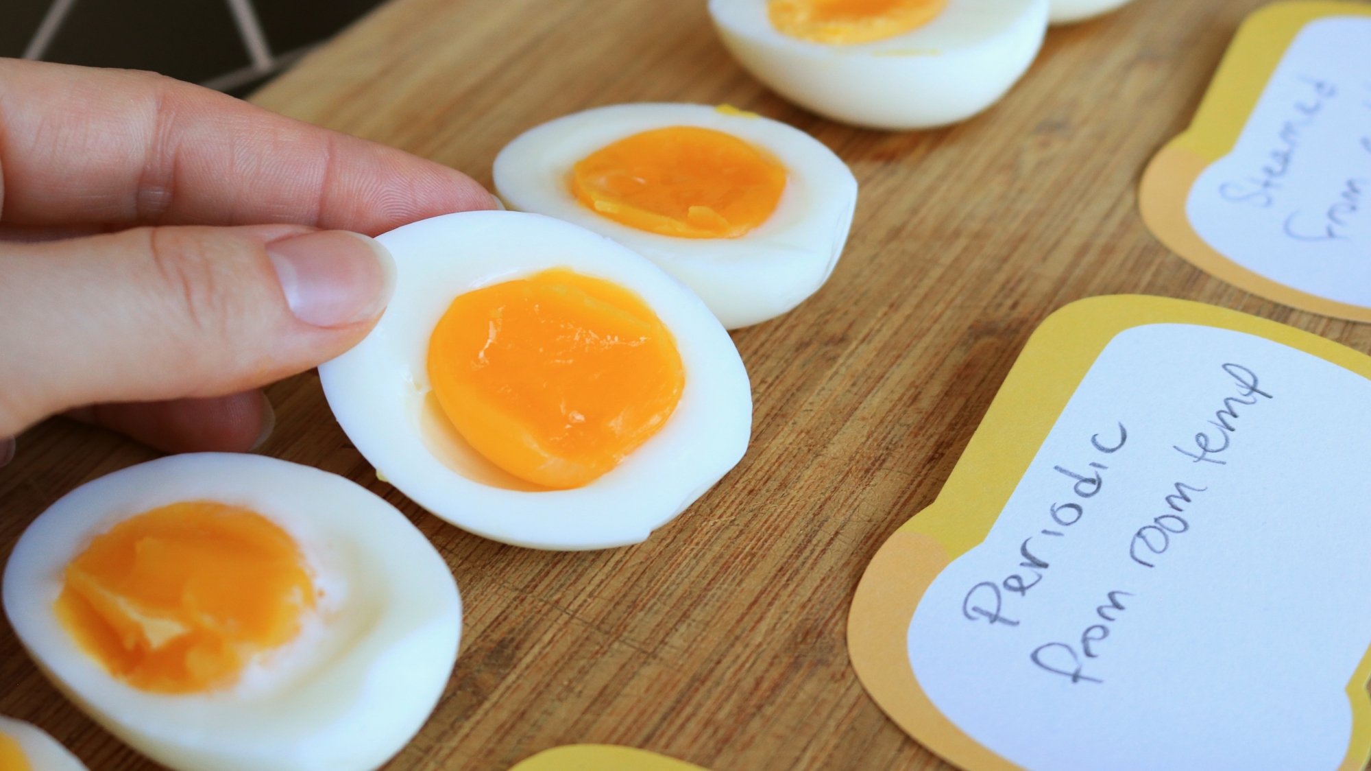 Boiled eggs cut in half and lined up on a cutting board.