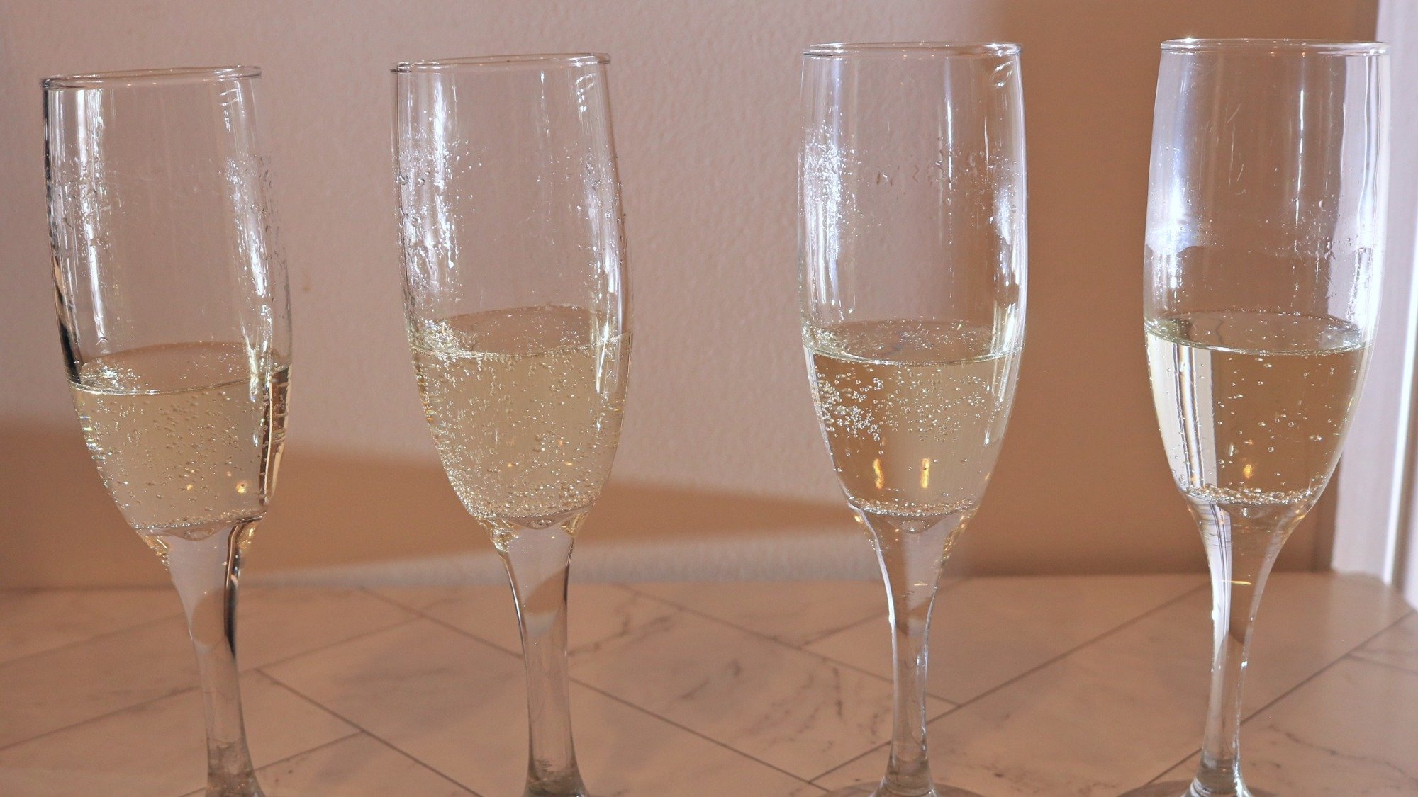 Four glasses of prosecco in champagne flutes.