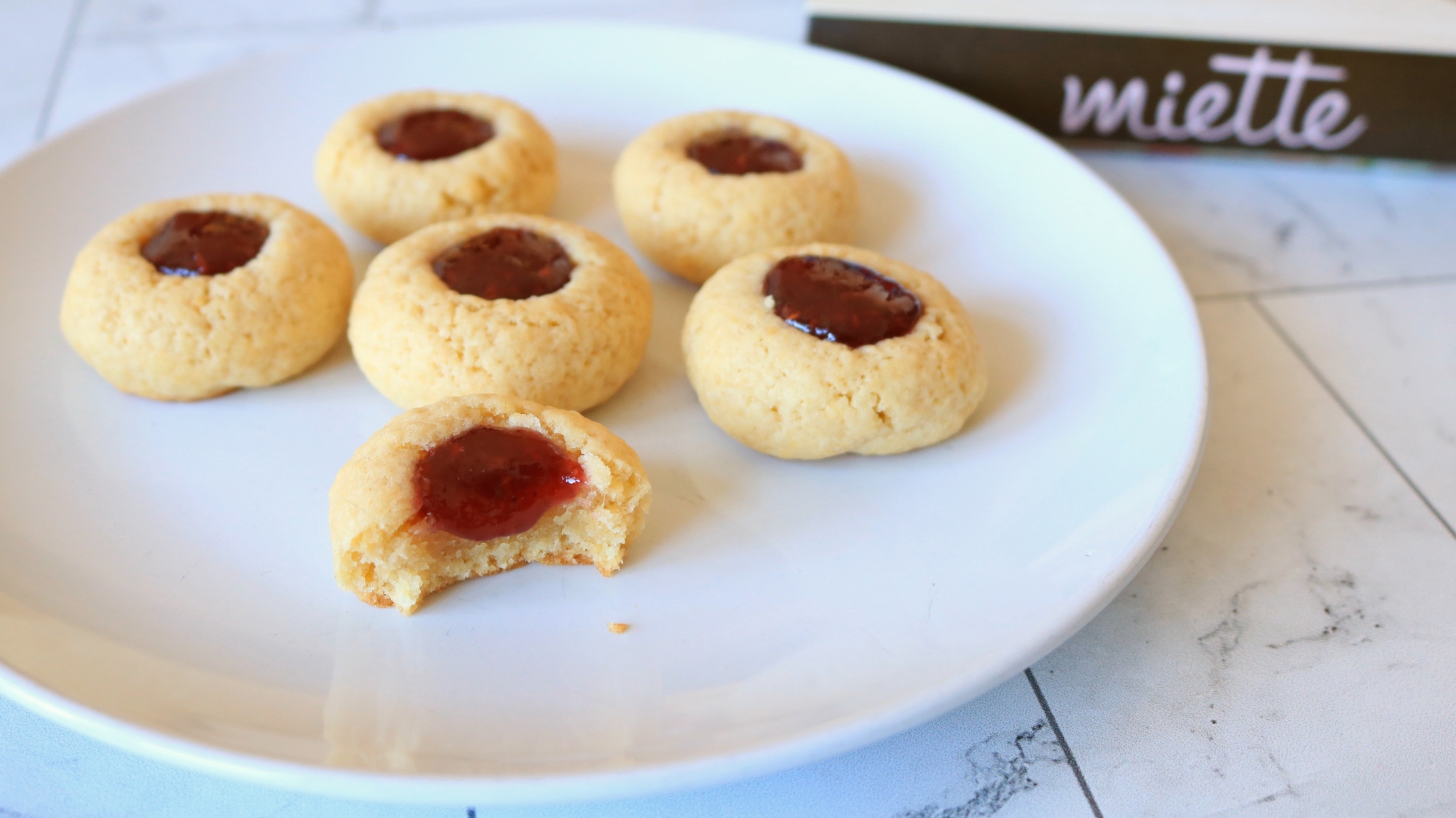 Raspberry thumbprint cookies on a plate.