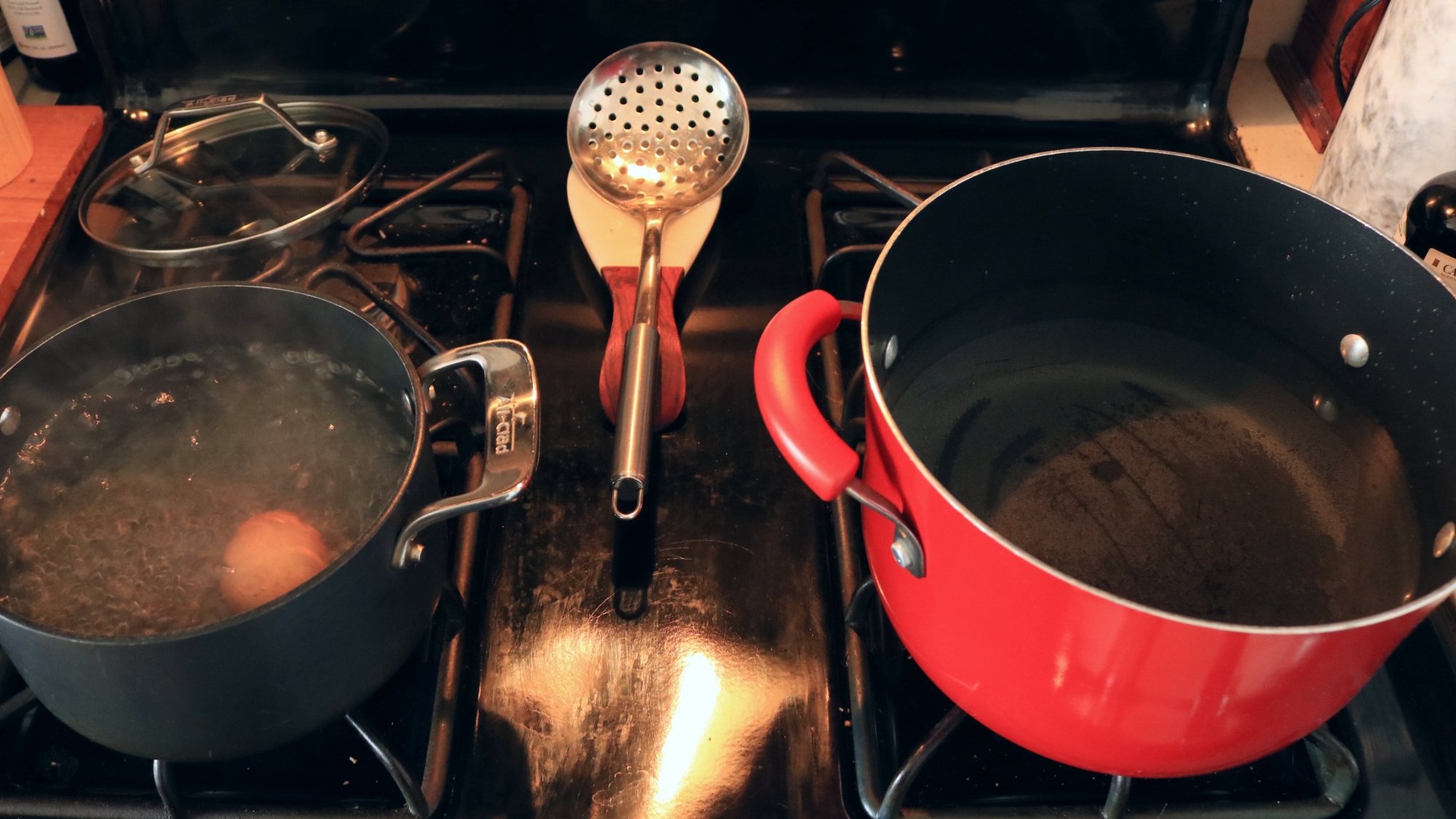 Two pots of water on a stove.