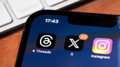 Smartphone showing X app logo next to Instagram and Threads