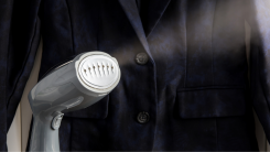 a handheld garment steamer on in front of a suit jacket