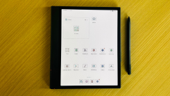 The Onyx Boox Note Air 4C on a table displaying the home screen with the pen accessory nearby