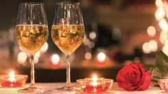 Two wine glasses on a table with soft lights in the background.