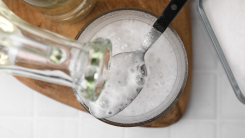 a bottle of vinegar is being poured over a spoonful of baking soda, causing a bubbly reaction