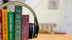 A stack of books standing vertically with a paid of headphones placed around them