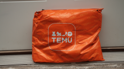 orange Temu package sitting against front door after being delivered