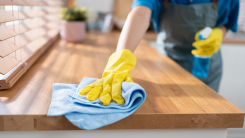 person wearing yellow rubber gloves and wiping a countertop down with a cloth