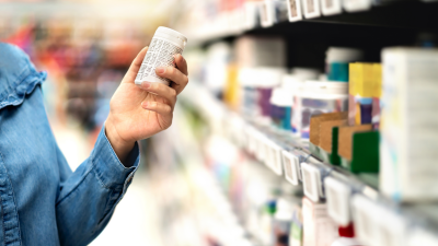 Customer in pharmacy holding medicine bottle. 