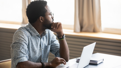 Man looking thoughtfully away from laptop