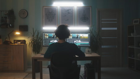 A woman sitting in front of two computer monitors in a dark room