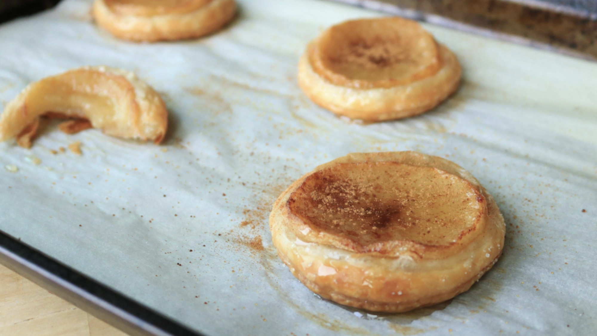 Round apple pastries on a sheet tray.