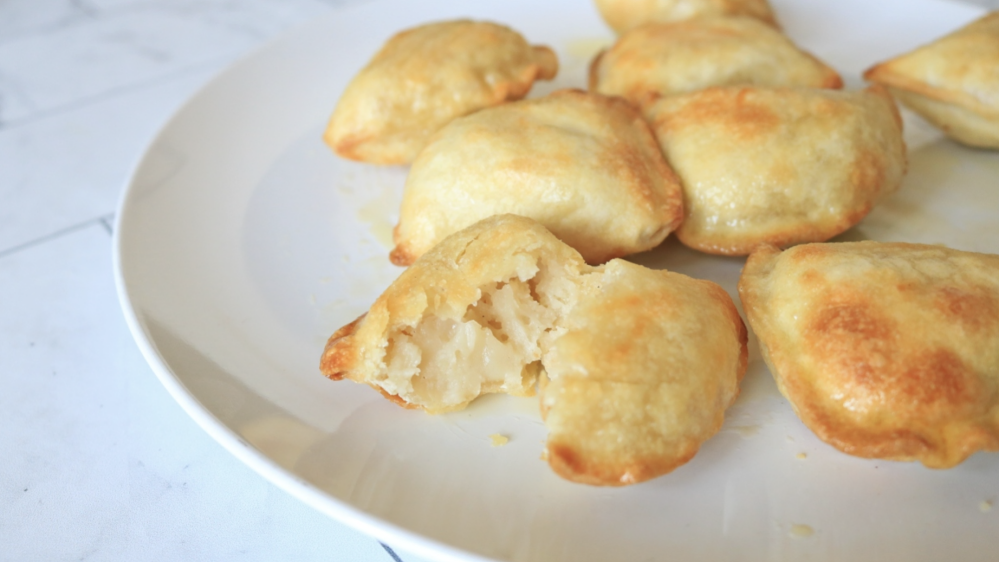 Golden pierogi on a white plate.