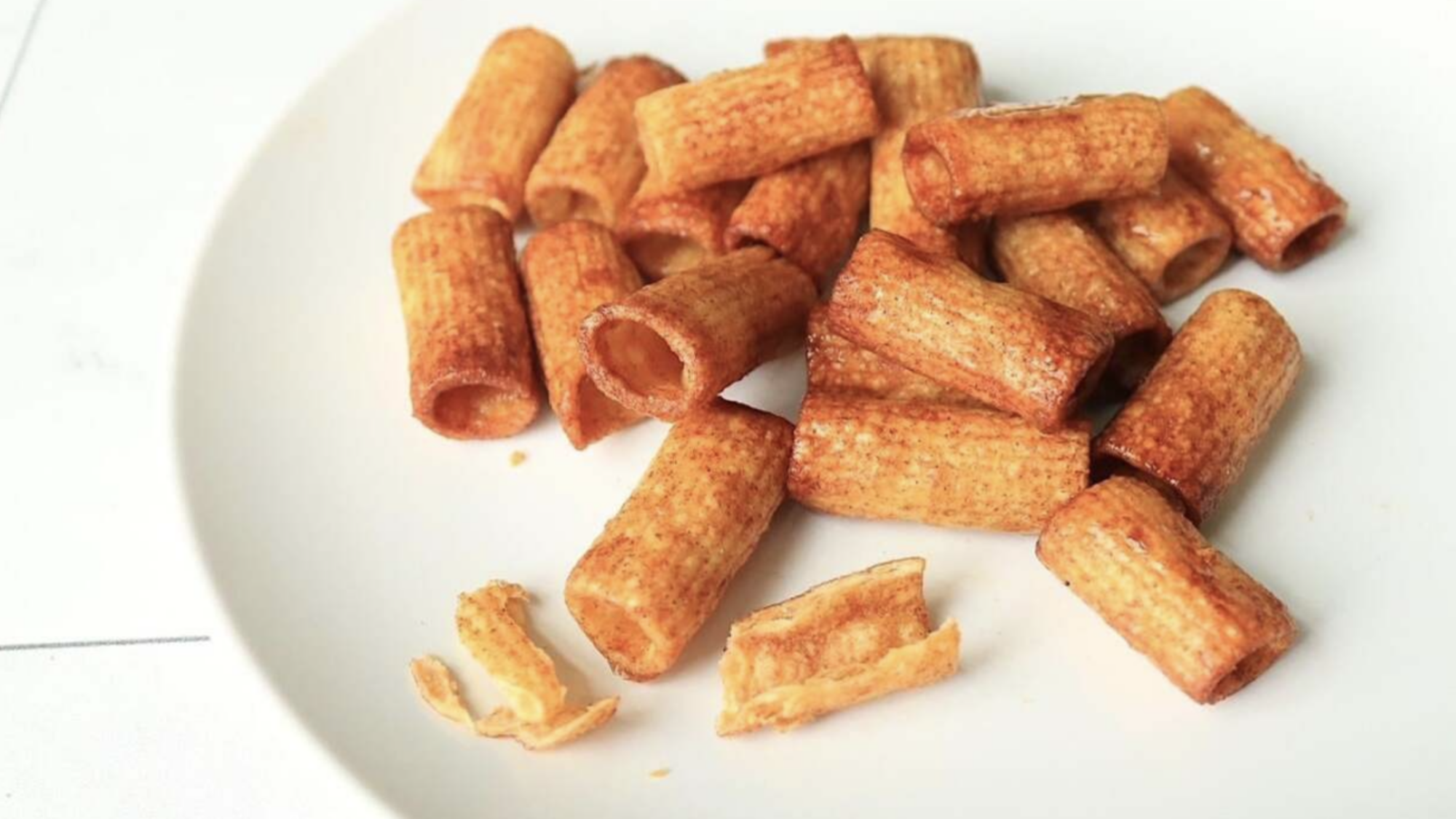 A plate with a mound of golden brown penne pasta chips.