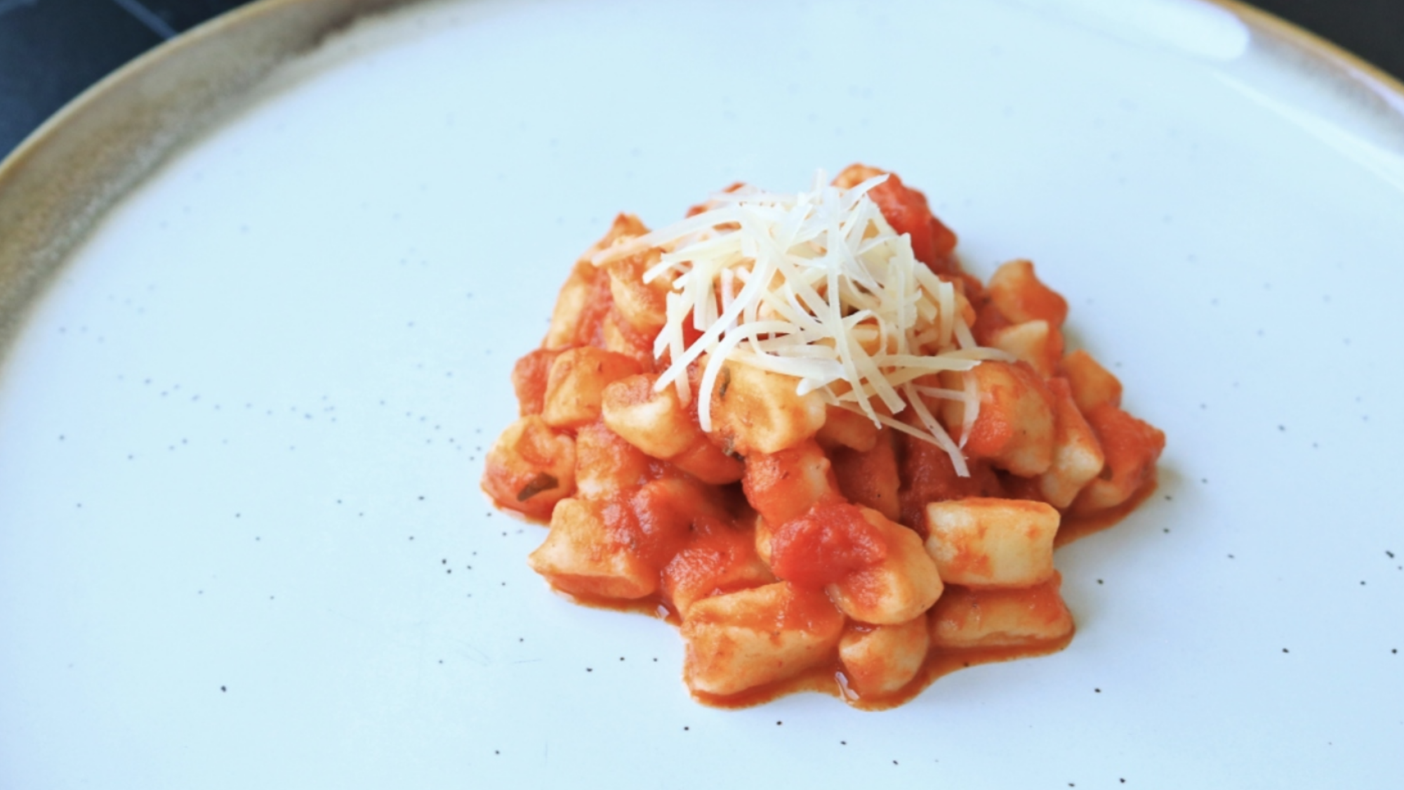 A plate with ricotta gnocchetti and tomato sauce in the center.