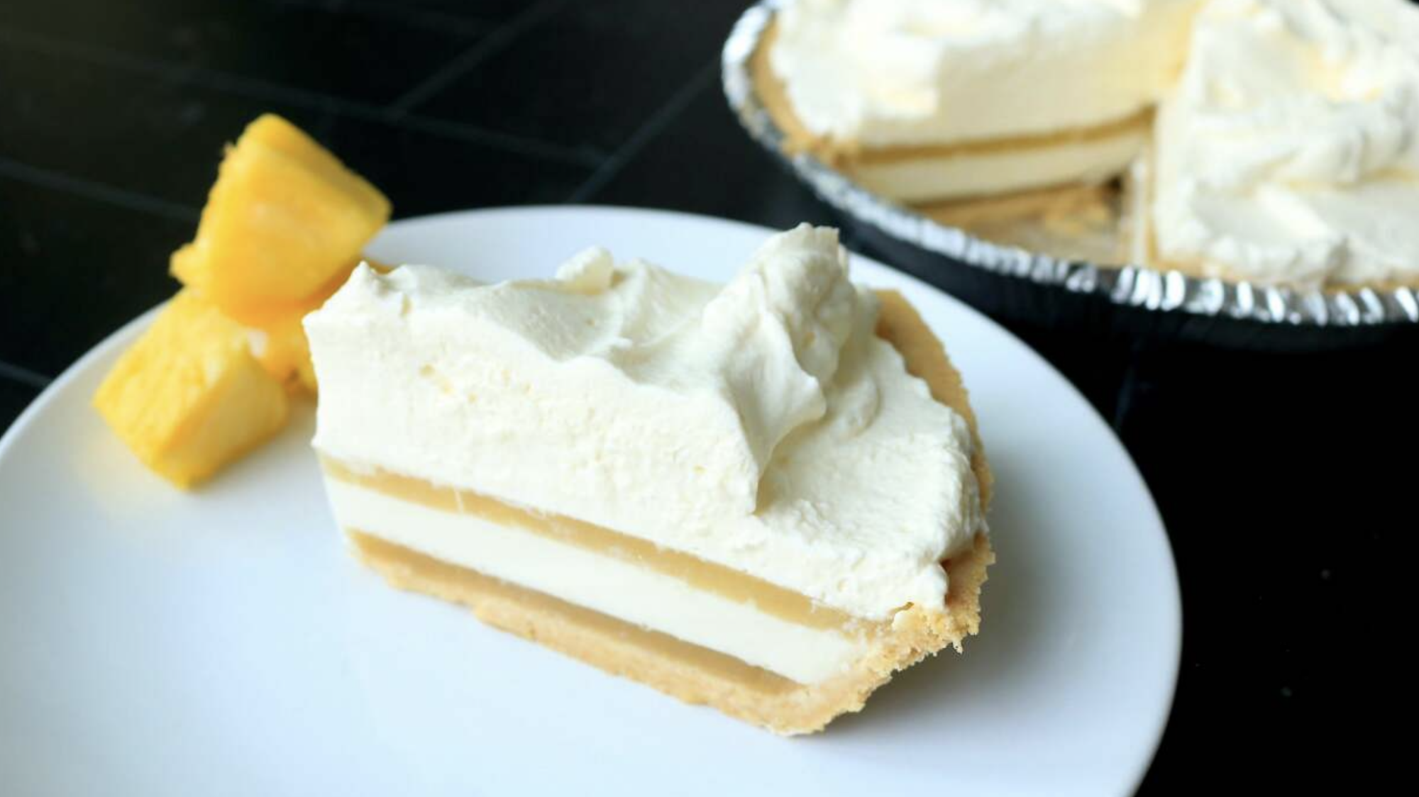 A coconut and pineapple pie with pineapple chunks next to it.