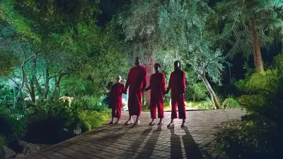 A group of people dressed in red looking ominously in a still from Us